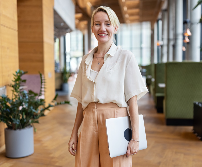 Smiling person holding laptop in modern office.