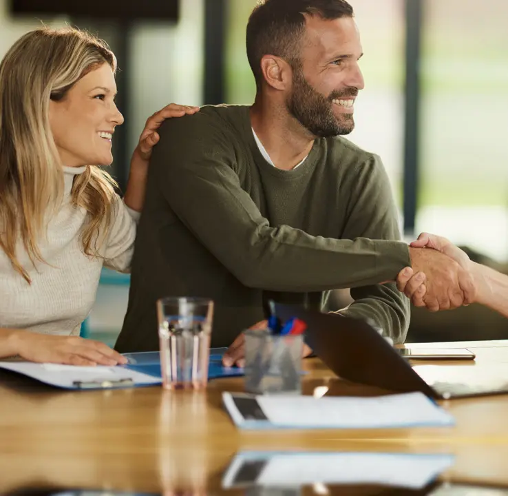 People shaking hands at a meeting table.