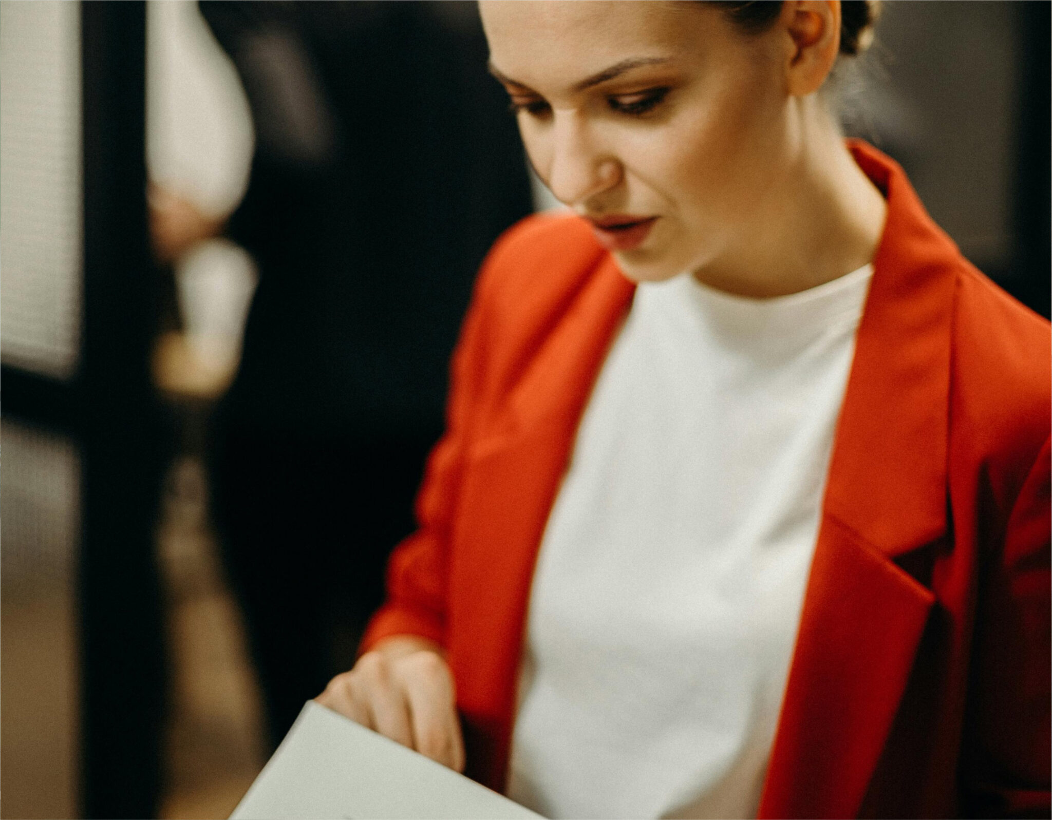 Woman in red blazer reading a document.