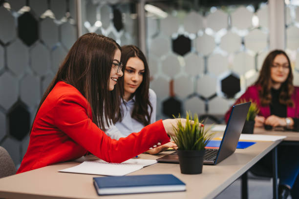 Women collaborating over laptop in office.