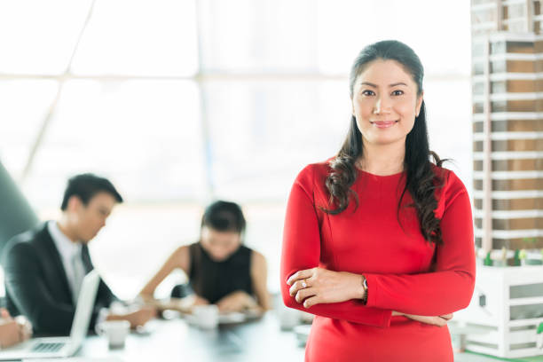 Woman in red dress standing, office background.