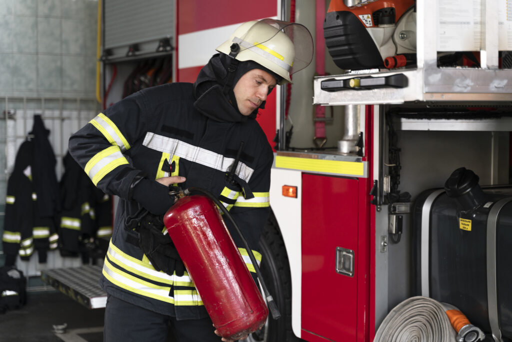 Firefighter with extinguisher near fire truck.