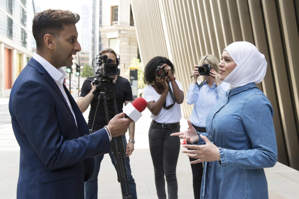Reporter interviews woman on city street.