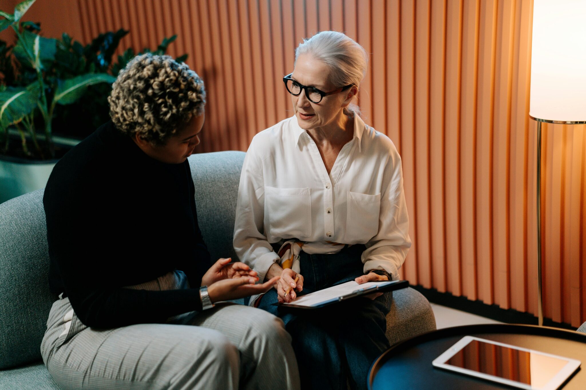 Two women discussing work on the sofa.