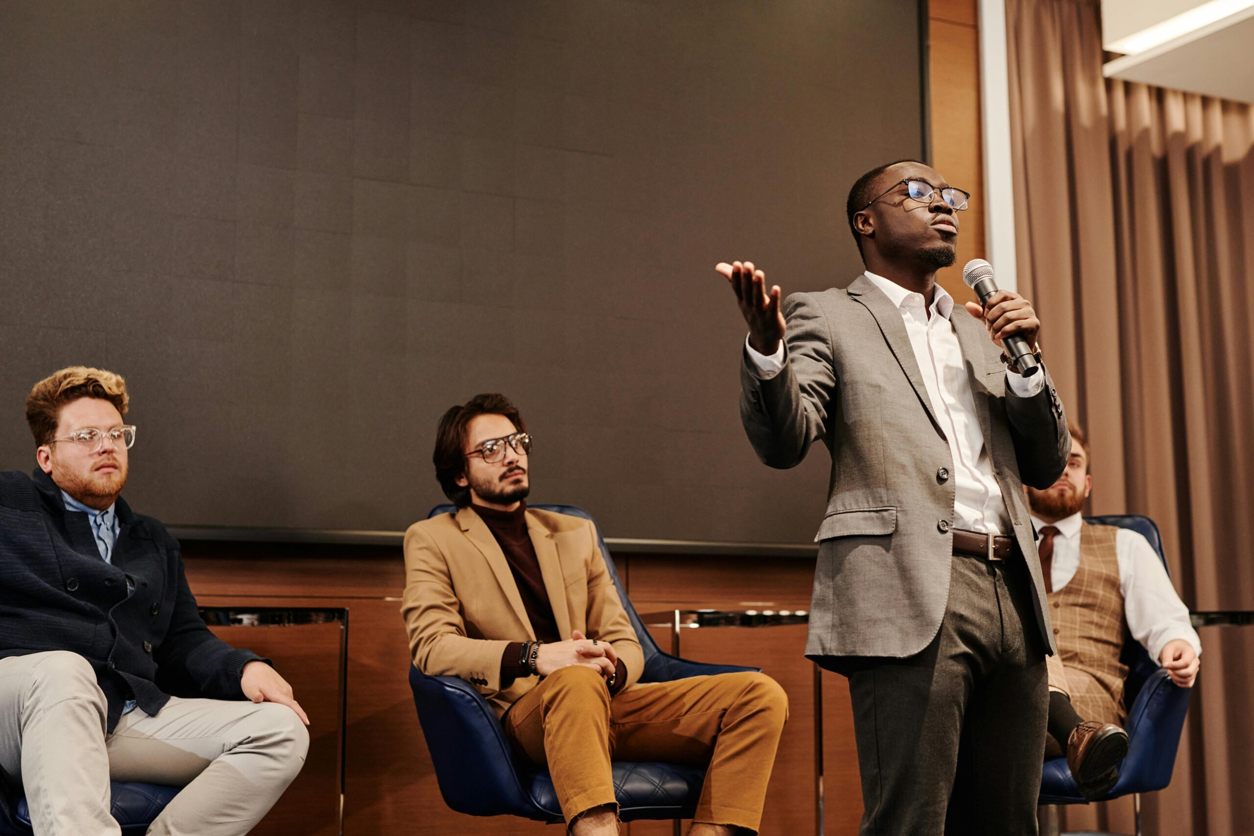 Confident presenter gesturing while speaking into microphone