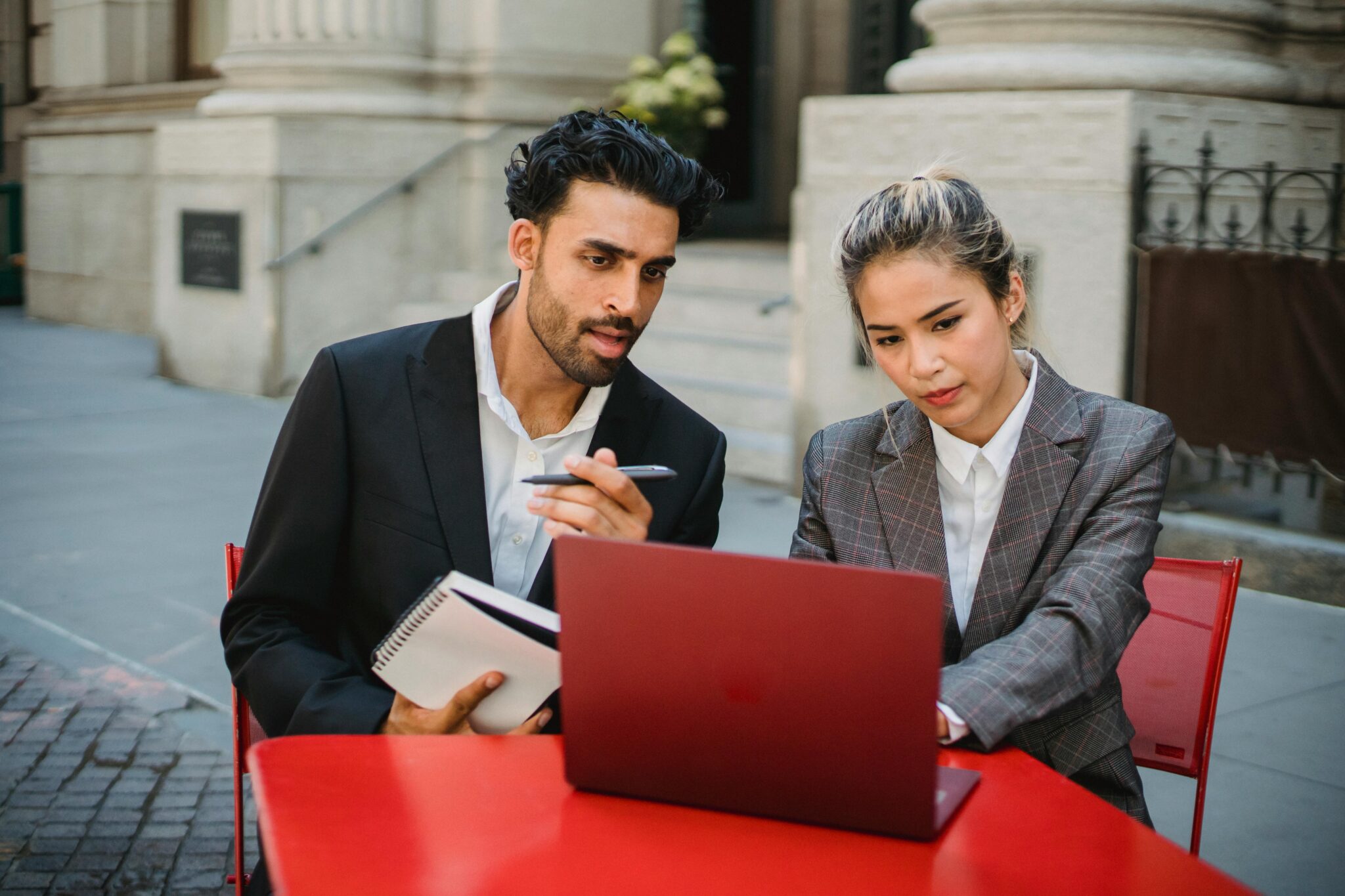 Two professionals discussing work on laptop.