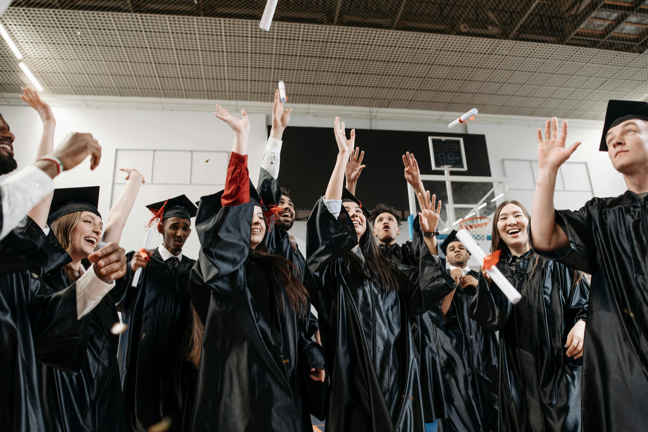 Smiling students in caps reaching for diplomas