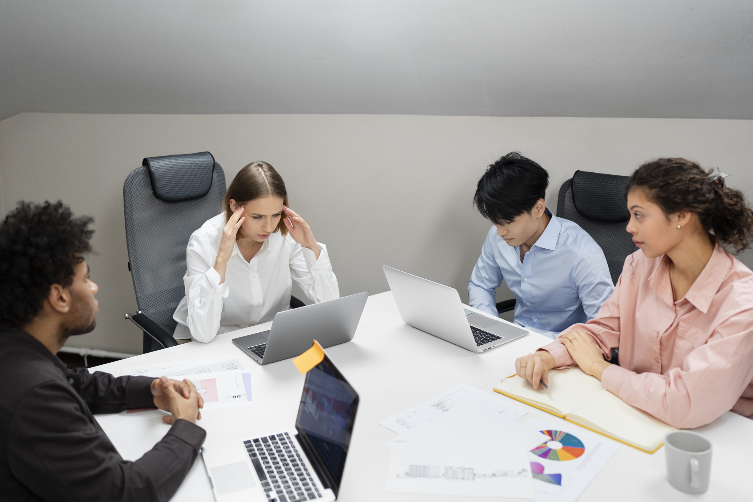 Four people in a meeting with laptops.